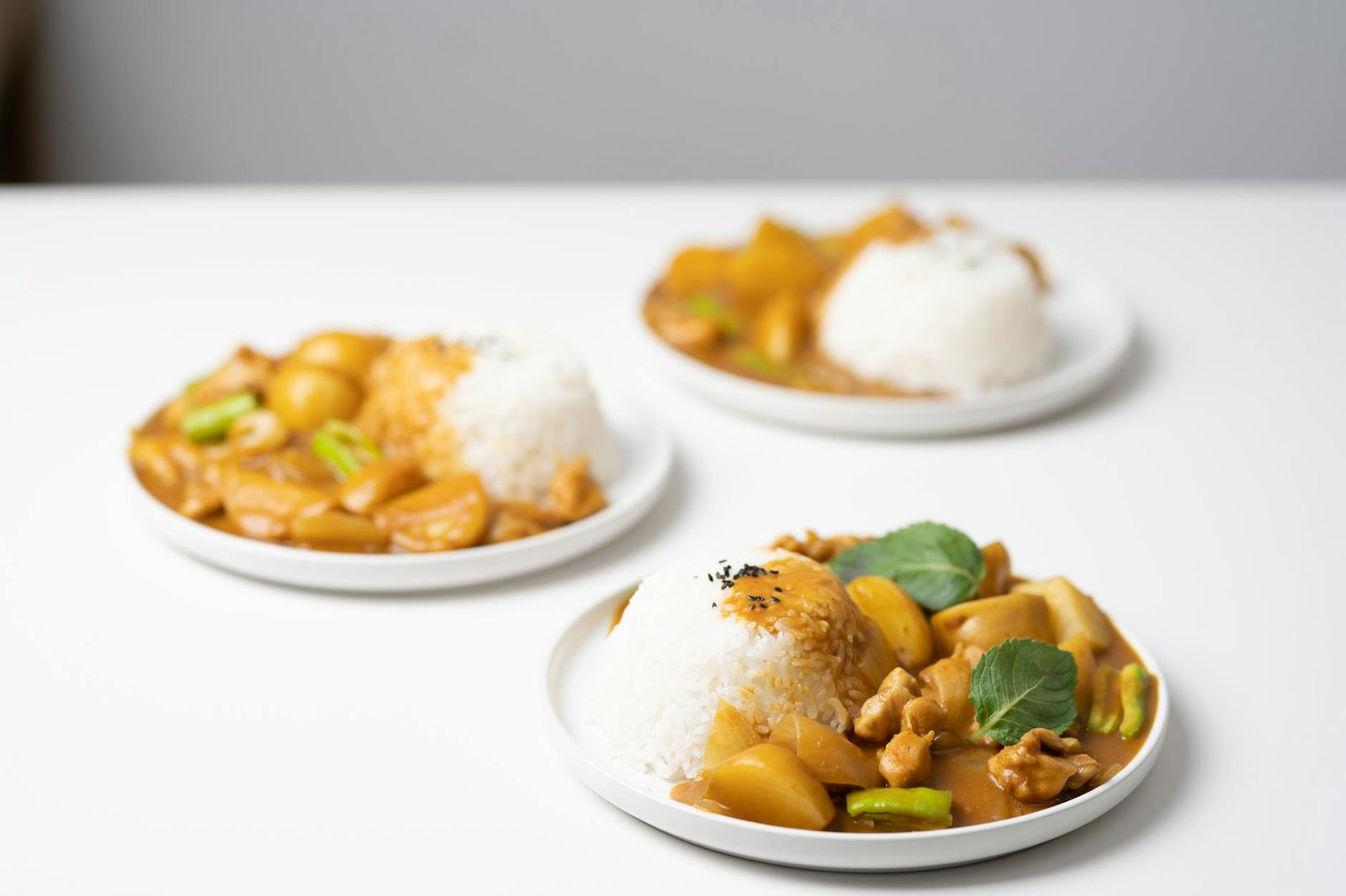 plates with tasty curry placed on white table